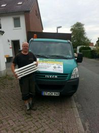 Eine Person steht vor einem grünen Lieferwagen und hält Heizkörperteile in den Händen.