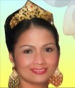 Frau mit goldener Kopfbedeckung und Ohrringen, Lächeln, vor hellem Hintergrund.