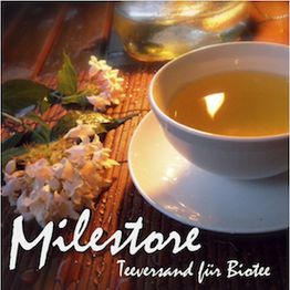 Tasse mit Tee und Blüten auf Holzuntergrund, Text: "Milestore, Teversand für Biotee".
