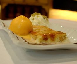 Postre en plato blanco: flan con helado de mango y nata montada.