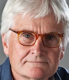 Älterer Mann mit grauen Haaren und Brille, blickt ernst in die Kamera.