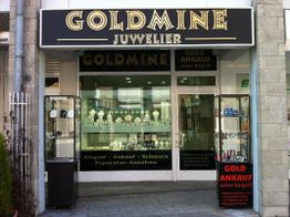 Juweliergeschäft „Goldmine“ mit Schaufenster voller Schmuck und Schild „Goldankauf sofort Bargeld“.