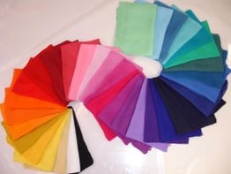 Stoffproben in Regenbogenfarben fächerförmig angeordnet auf einer weißen Oberfläche.