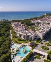 Complejo turístico frente al mar con piscinas rodeado de vegetación.