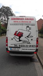 Lieferwagen der "Lüneburger Umzüge" mit Firmenlogo und Kontaktdaten auf einer Straße.