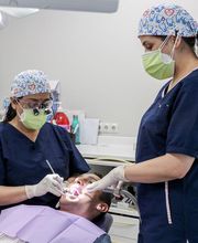 Dos dentistas atienden a un paciente en una clínica dental moderna.