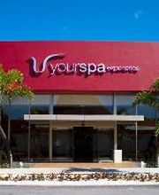 Fachada de spa moderno con palmeras y cielo azul.