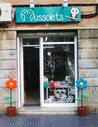 Tienda "Mussolets" con flores decorativas de colores en la entrada.