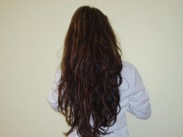 Person mit langen, braunen Haaren von hinten, trägt eine weiße Bluse.