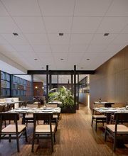 Restaurante moderno e elegante, mesas com louças, decoração minimalista e iluminação suave.