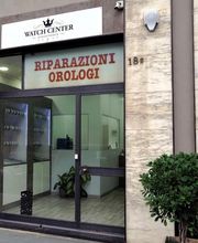 Facciata di un negozio di riparazione orologi con porta in vetro e insegna "WATCH CENTER".