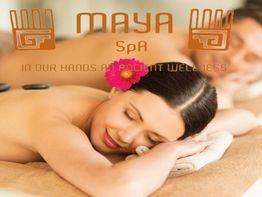 Pareja descansando en spa, mujer sonríe con flor en el cabello. Texto: Maya Spa.
