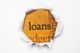 Torn paper revealing the word "loans" on a textured orange background.