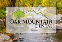 Oak Mountain Dental logo over a serene forest stream scene with rocks and green trees.