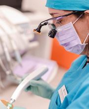 Trabajadora de la salud con equipo dental y uniforme azul, operando instrumentos médicos.