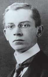 Schwarz-weiß Porträt eines Mannes mit Brille und Anzug, ernst blickend.