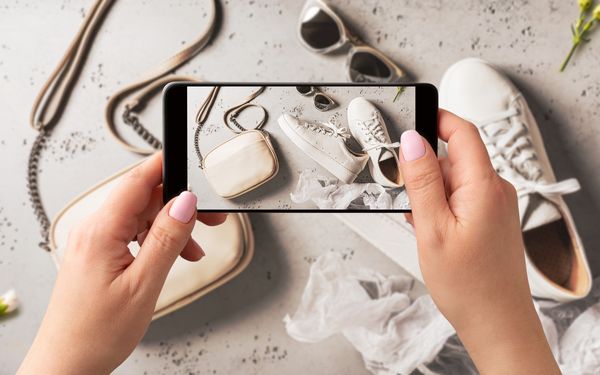 Eine Frau fotografiert Fashion Produkte mit ihrem Handy, für ihren Shop auf ihrer Website.