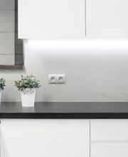 Cocina moderna blanca con encimeras negras y macetas pequeñas decorativas.