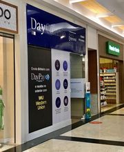 Corredor de shopping com lojas, manequins vestidos e placa de transferência de dinheiro.