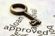 A brass key on paper with the words "loan" and "approved" visible.