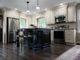 Elegant kitchen with dark island, pendant lights, and stainless steel appliances.
