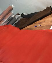 Varias pieles en diferentes colores sobre una mesa de trabajo, junto a una calculadora y libreta.