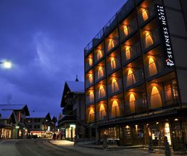 Beleuchtetes Hotel in winterlicher Stadtstraße bei Abenddämmerung.
