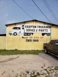 Yellow building with a truck mural advertising "Keep'em Trucking Service & Parts" with a phone number.