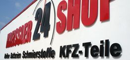 Großes Schild mit der Aufschrift "SHOP 24" und "KFZ-Teile" in Rot und Schwarz.