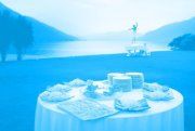 Ein gedeckter Tisch mit Kuchen, im Hintergrund ein See in Berglandschaft.