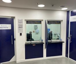 Porta azul com placas "Acesso Restrito" e "Sala VIP" ao lado de guichês de atendimento.