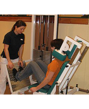 Eine Trainerin hilft einer Person bei der Beinpresse im Fitnessstudio.