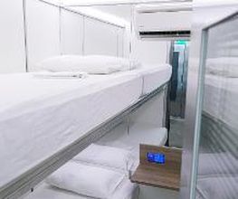 Cama beliche em cabina moderna e minimalista com luzes brancas.