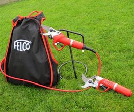 Rucksack mit "Felco"-Logo, verbunden mit elektrischen Gartenscheren, auf grünem Rasen.