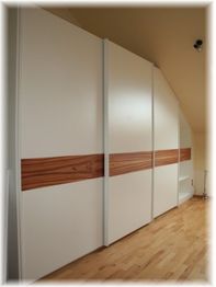 Einbauschrank mit weißen Schiebetüren und hölzernen Akzenten auf hellem Holzboden.