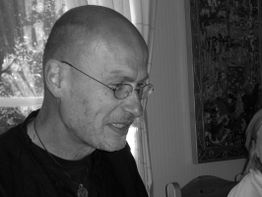 Ein Mann mit Brille und Glatze in einem Zimmer, schwarz-weiß Foto.