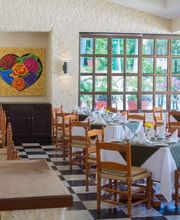 Restaurante colorido con mesas preparadas, ventanales grandes y pintura de corazón en la pared.