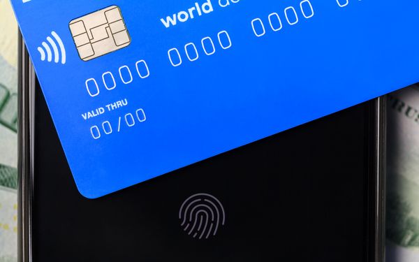 Eine Paysafe Card liegt auf einem gesperrten Smartphone Display auf dem ein Fingerabdrucksensor zu sehen ist.