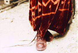 Rote Samthosen und braune Schnürstiefel auf hellem Untergrund.