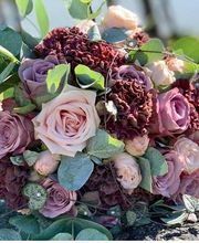 Ramo de flores con rosas rosadas y hortensias moradas, rodeado de hojas verdes.