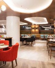 Restaurante elegante con sillas rojas y marrones, mesas listas y decoración moderna.