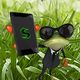 Frosch im Anzug und Sonnenbrille, hält ein Smartphone vor einer Wiese.