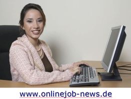 Eine Frau sitzt lächelnd am Schreibtisch und tippt auf einer PC-Tastatur.