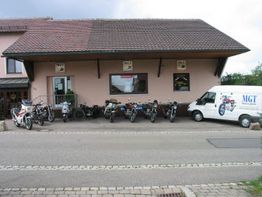 Gebäude mit geparkten Motorrädern davor und einem weißen Lieferwagen daneben auf der Straße.