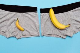 Graue Boxershorts mit Banane und kleiner Banane, auf blauem Hintergrund.