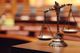 Bronze scales of justice on a desk, blurred courtroom in the background.