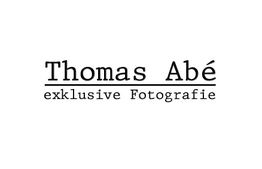 Text: "Thomas Abé - exklusive Fotografie" in schwarzer Schrift auf weißem Hintergrund.