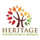 Logo of Heritage Custom Signs & Displays with a colorful tree design.