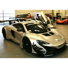 Silver sports car with open doors in a showroom.
