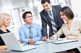 Pessoas trabalhando juntas em uma reunião de negócios, com papéis e laptop na mesa.